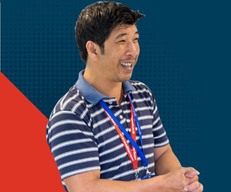 tutor standing in front of dark blue and red background