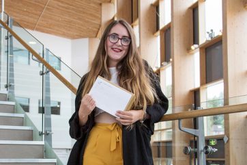 student holding results on campus stairs