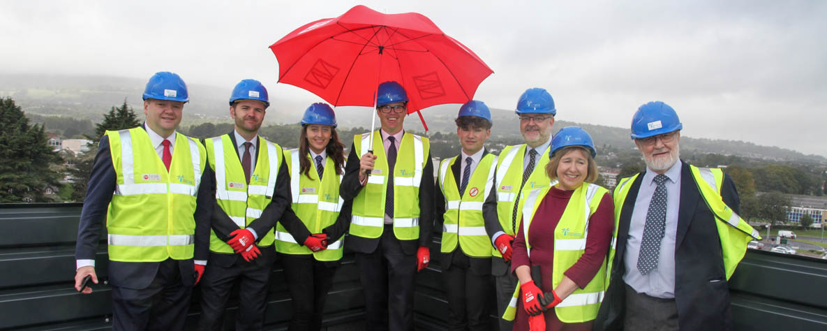 People in hi viz on the TLZ roof with a red umbrella