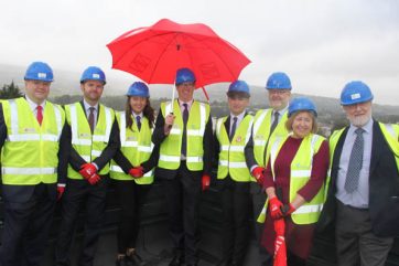 People in hi viz on the TLZ roof with a red umbrella