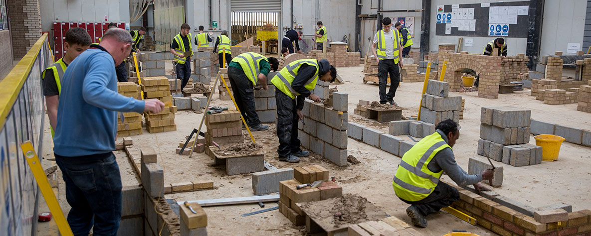 Learners in hi-viz laying bricks and blocks