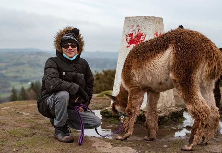 Coleg Gwent student at trig point with llama