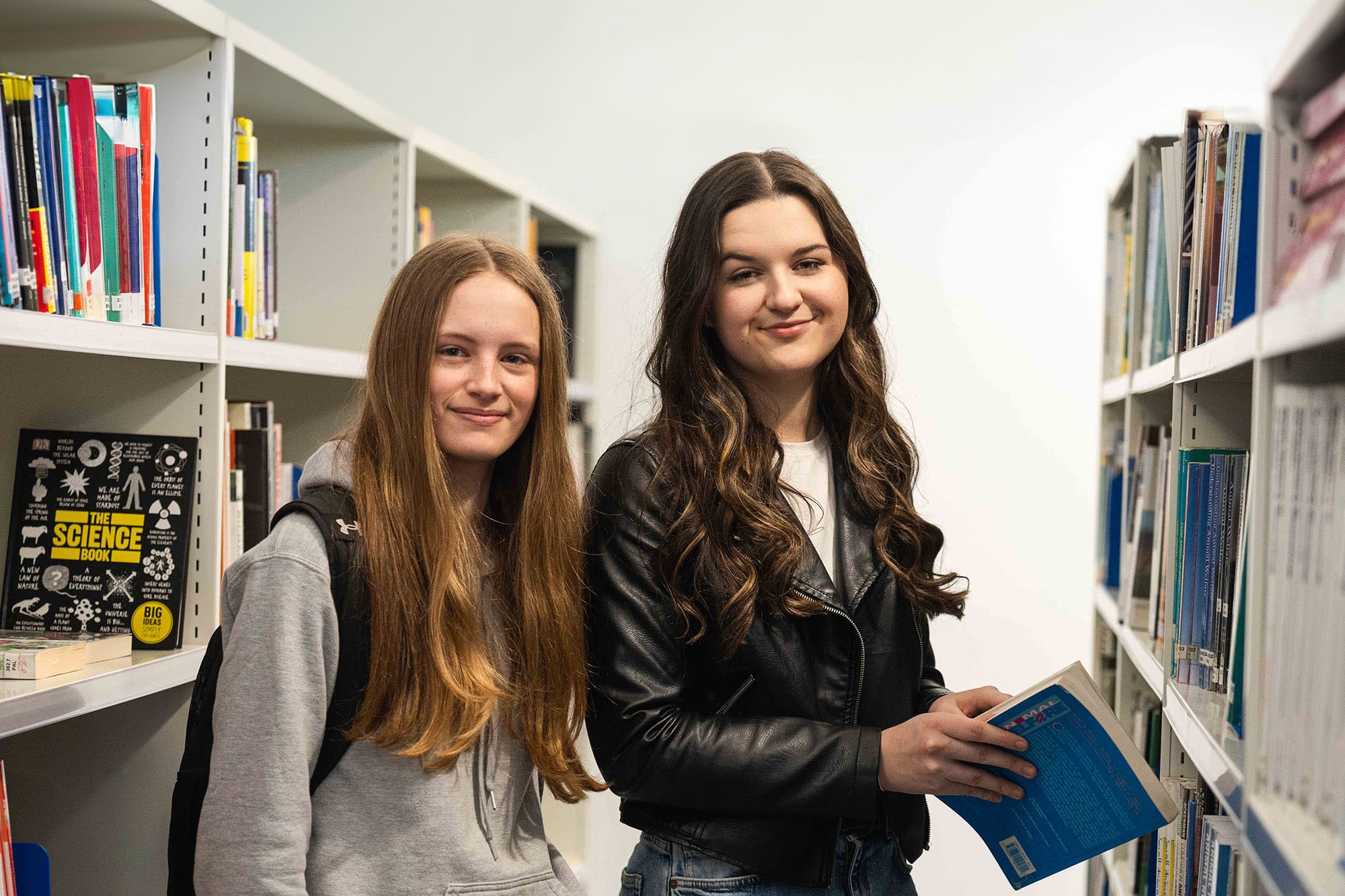 Two students holding book in Usk library