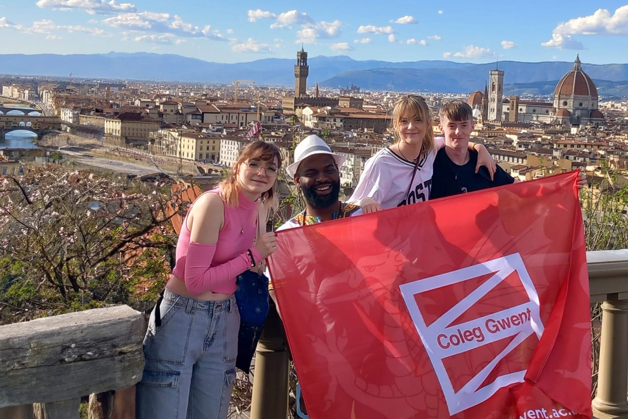 Students smiling holding a 91�㽶��Ƶ flag in Italy