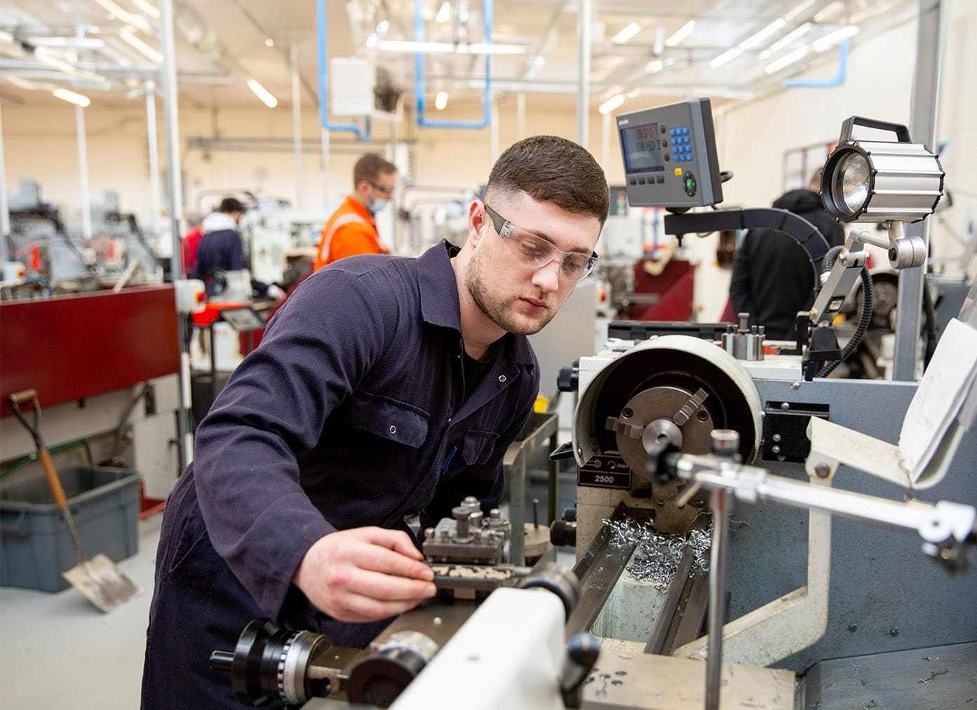 Engineering student wearing overalls and operating machinery