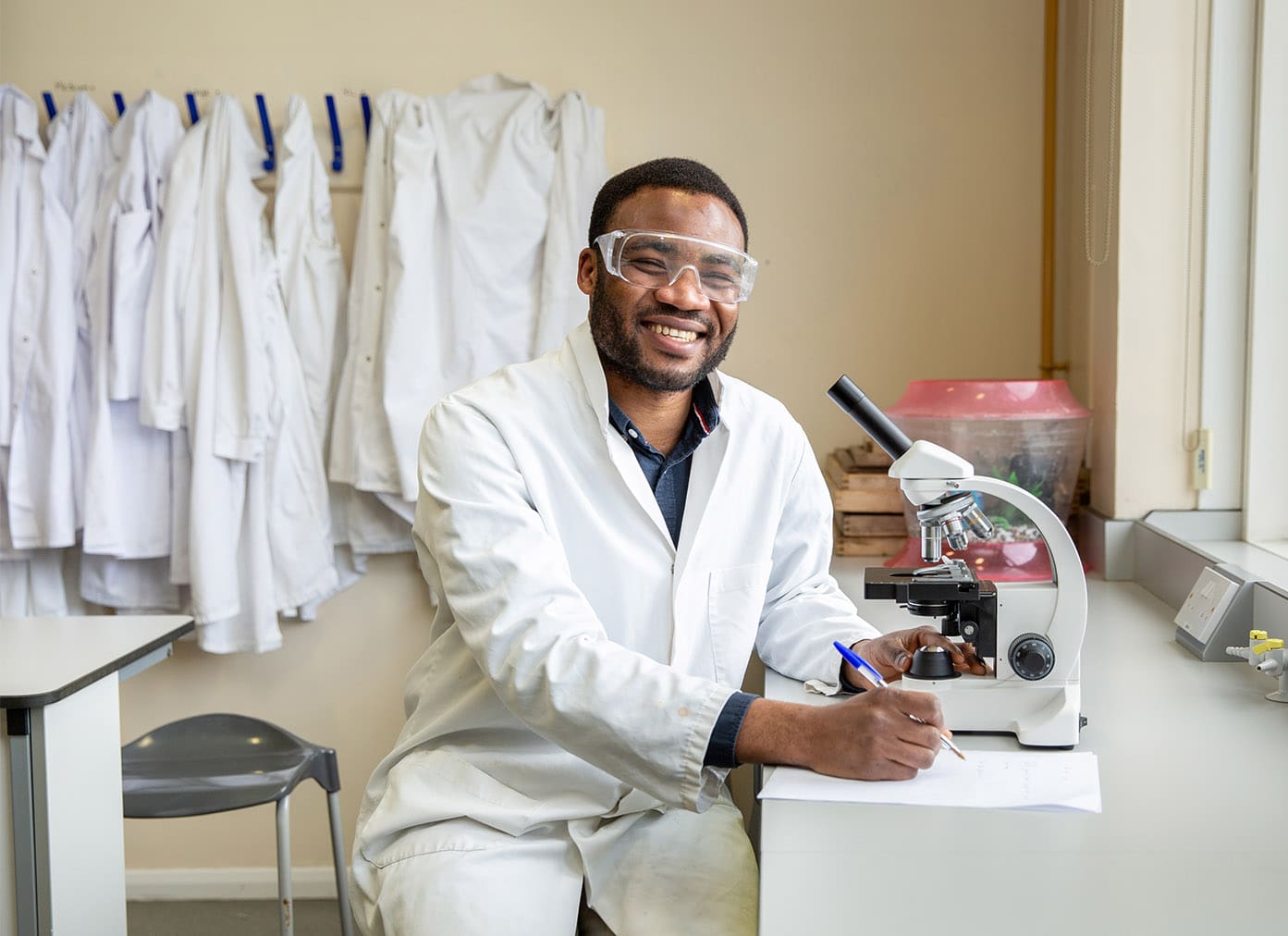 Science student wearing a lab coat and using a microscope