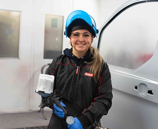 Apprentice in workplace with car paint spray gun
