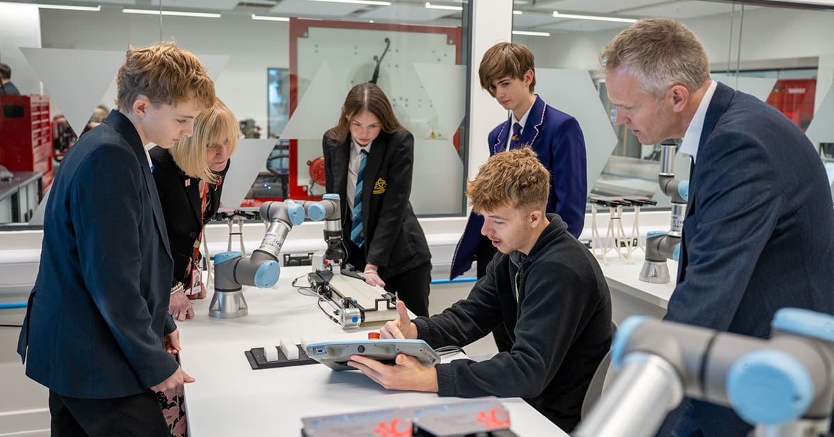 Students demonstrating robotic arms using a tablet