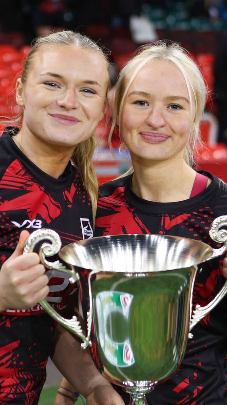 Rugby players smiling and holding a trophy